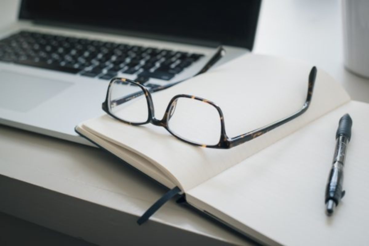 Image of a computer with book and glasses